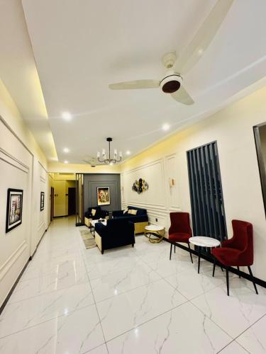 a living room with a black couch and red chairs at Holiday One Hotel & Suites - Expo Center in Karachi