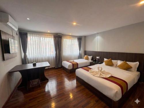 a hotel room with two beds and a desk at Hotel In N Out in Kathmandu
