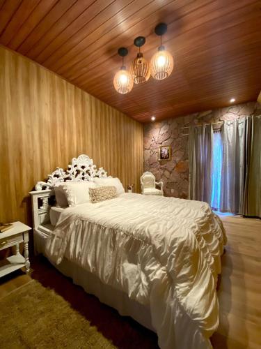 a bedroom with a large white bed and lights at Pousada Sítio Bosque in Campina Grande