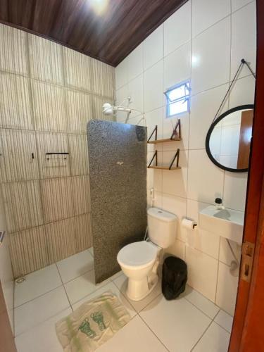 a bathroom with a toilet and a sink and a mirror at Lotus Beach in Piaçabuçu