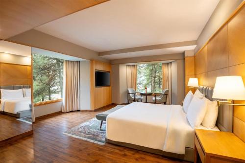 a hotel room with a large bed and a desk at Radisson Golf Resort Pahalgam in Pahalgām