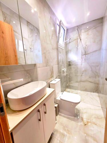 a white bathroom with a sink and a toilet at Anthouli homes 4, steps from beach and centre in Kardamaina