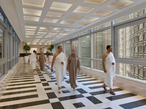 a group of people walking down a hallway in a building at Swissotel Al Maqam Makkah in Mecca