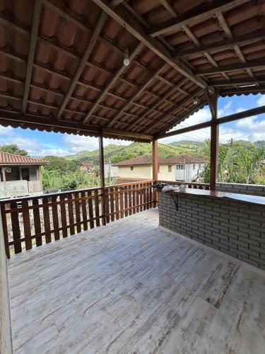 a large wooden deck with a roof with a view at Chalé samambaia in Resende