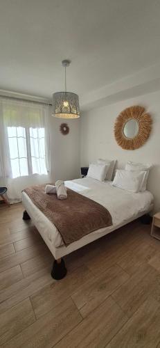 a bedroom with a large bed and a mirror at havre de paix a la Sologne in Veilleins