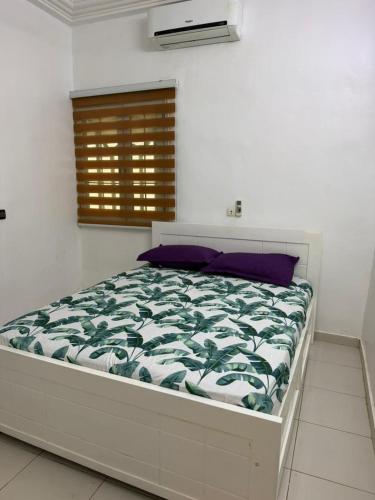 a bedroom with a bed with a green and white comforter at Jfk3 in Ouagadougou