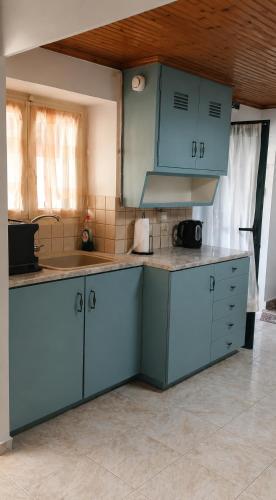 a kitchen with blue cabinets in a room at Τα σπίτια στα Λειβάδια - Γαρδένια in Vrakhnós