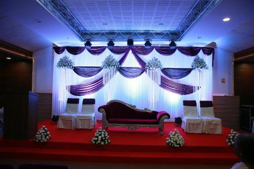 a room with a couch and a stage with curtains at KGA Elite Continental Hotel in Thiruvalla
