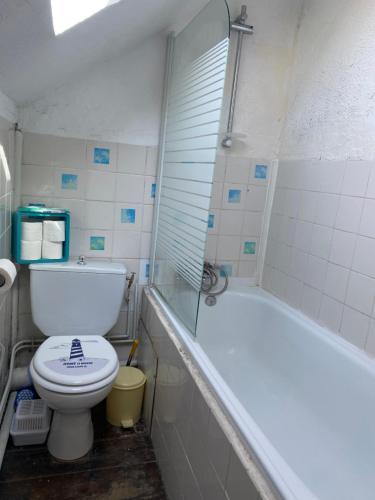 a bathroom with a toilet and a bath tub at Maison de pêcheurs les petits quinquins in Étaples