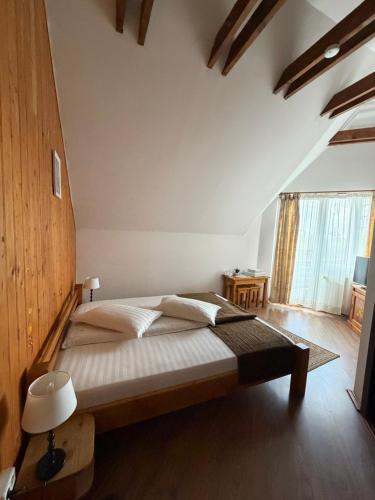 a bedroom with a large bed with a wooden headboard at Vila Alisa in Bran
