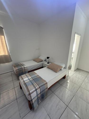 two beds in a white room with a window at Apartamento Tio Du in Sorocaba