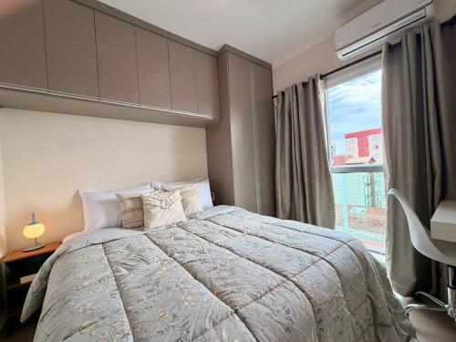 a bedroom with a bed and a large window at Apartamento Unicco 25, next to USP in São Carlos