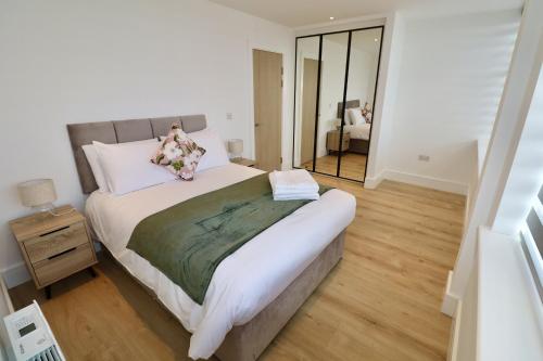a bedroom with a large bed and a mirror at Chertsey Modern 2-Bed Flat with Parking in Chertsey