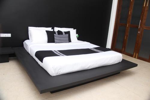 a bed with black and white pillows on a black platform at Ariya Tissa in Tissamaharama