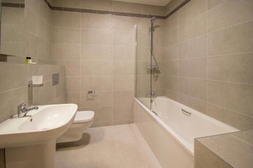 a bathroom with a sink and a toilet and a bath tub at The Maltings in Portlaoise