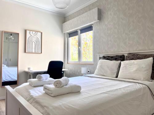 a bedroom with a large white bed with towels on it at Quarto confortável in Amadora