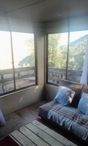 a bed in a room with large windows at Cabaña Ecologica Huinganes in Machalí