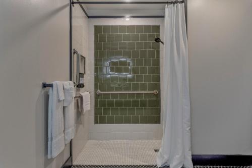 a bathroom with a shower with green tile at Hotel Biloxi in Biloxi
