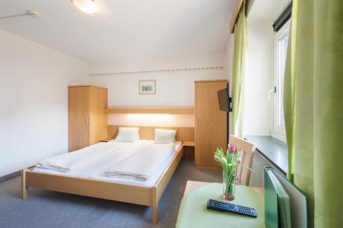 a small bedroom with a bed and a table at Hotel Linde in Wörgl