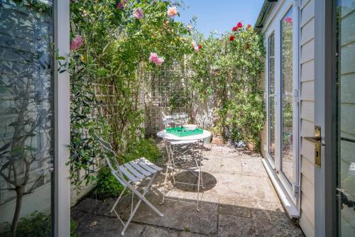 a patio with a table and chairs and roses at Christmas Cottage in Yarmouth