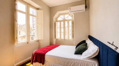 a bedroom with a bed with a red blanket and a window at Odara Hostel & Guesthouse in Salvador