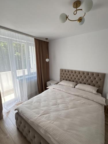 a bedroom with a large bed and a window at Caro Central Apartament 3 Camere in Râmnicu Vâlcea