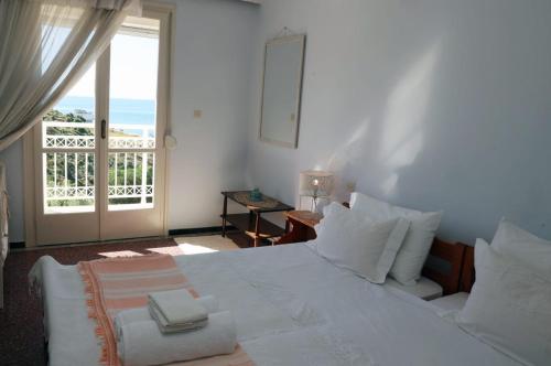 a bedroom with a large white bed with a balcony at Sea view apartment in Plomari