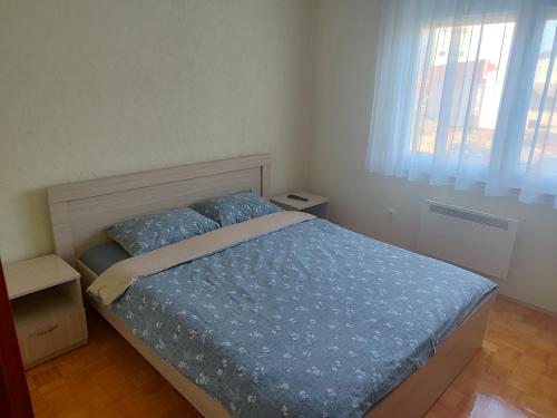 a bedroom with a bed with blue comforter and two pillows at Apartman Mimi in Bratunac