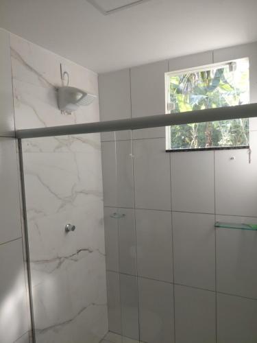 a bathroom with a glass shower with a window at Pousada Jardim de Pedras in Pancas