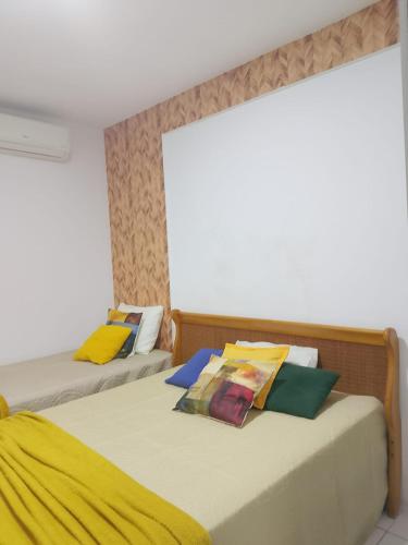 two beds with colorful pillows in a room at Apto Tropical - Enseadas dos Corais in Cabo de Santo Agostinho