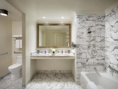 a bathroom with a tub and a sink and a toilet at Fairmont Orchid in Waikoloa