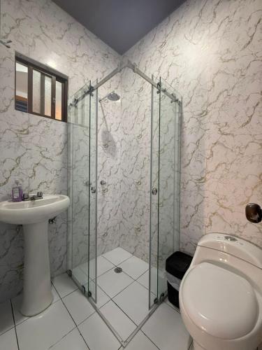 a bathroom with a shower and a toilet and a sink at Hostal Café Tiana in Latacunga