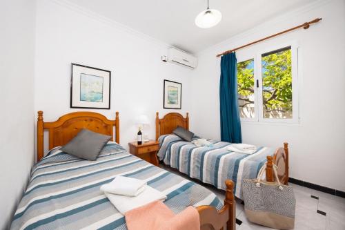 a bedroom with two beds and a window at Villa Emilio in Cala en Porter