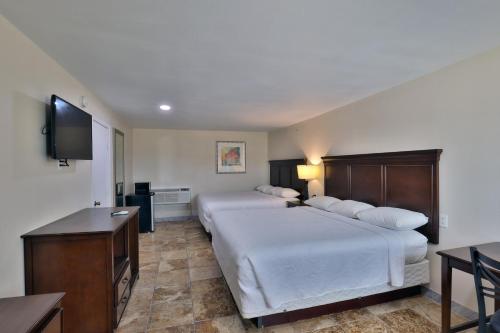 a hotel room with two beds and a flat screen tv at Monterrey Motel Padre Island, Corpus Christi BY OYO in Padre Island