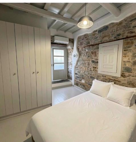 a bedroom with a white bed and a brick wall at Samos Vista Azzurra 2 in Samos