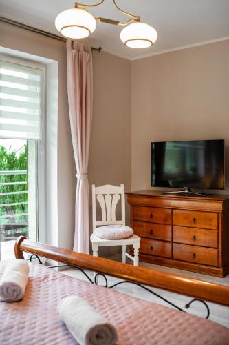 a bedroom with a tv and a bed and a dresser at Wenge in Jastarnia
