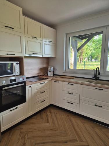 a kitchen with white cabinets and a large window at MarioLia Comfort Residence in Oradea