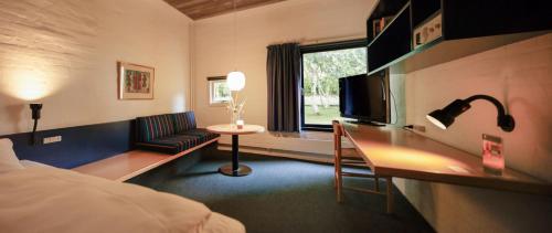 a hotel room with a bed and a desk with a television at Kysthotellet in Grenå
