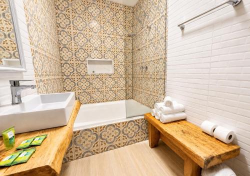 a bathroom with a sink and a tub and a table at Empório reserva da serra - Opções de chalés e Hidromassagem in Campos do Jordão