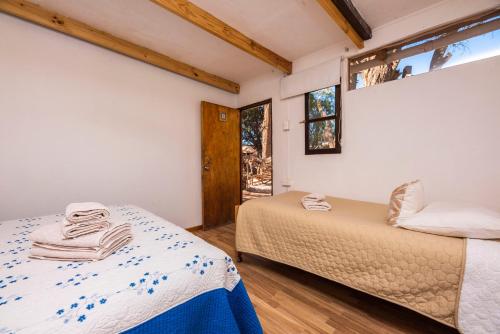 a bedroom with two beds and a window at Hotel-Camping Takha Takha in San Pedro de Atacama