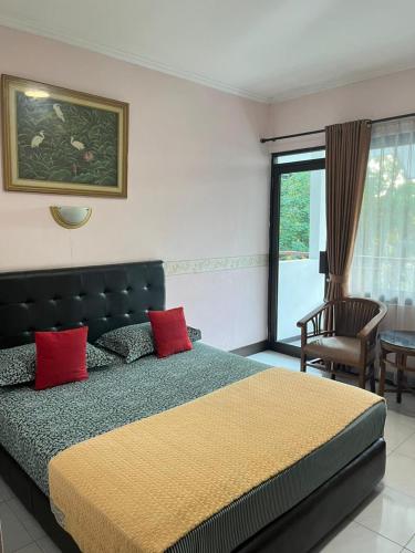 a bedroom with a bed with red pillows and a chair at Wisma Pakuan Syariah Hotel in Bogor