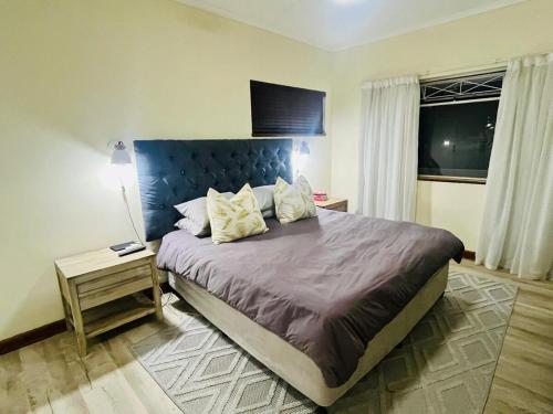 a bedroom with a large bed with a blue headboard at Pleasance Flat nr 8A Worcester Street in Grahamstown