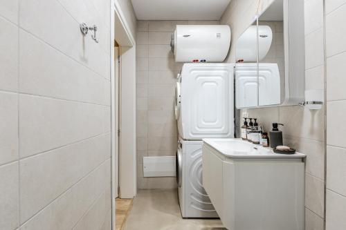 a white laundry room with a refrigerator and a sink at NooN Apartment | Sofo Duni by PikHost in Dhërmi