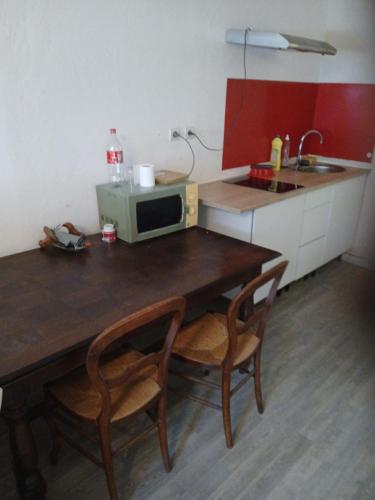 a kitchen with a table with two chairs and a microwave at Appartement entier in Montmarault