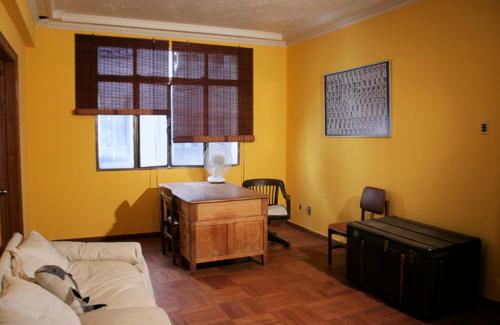 a living room with yellow walls and a couch and a desk at Pascua 2-baño compartido in Santiago