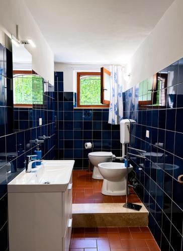 a blue tiled bathroom with two toilets and a sink at Casa Maddalena in Monteriggioni