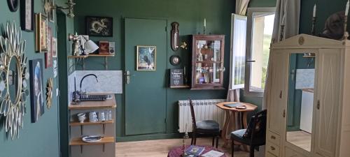 a room with a green wall with a table and chairs at La Maison d'Osquich in Musculdy