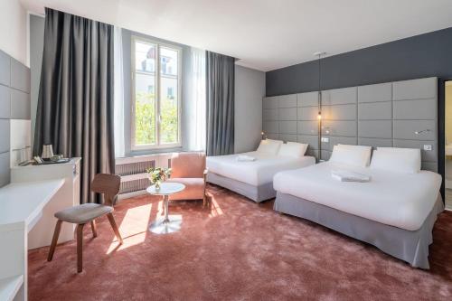 a hotel room with two beds and a chair at Best Western Dijon Centre Gare in Dijon