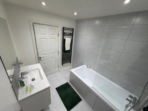 a white bathroom with a tub and a sink at Stylish Charming London Flat Ruislip -Free Parking in Ruislip