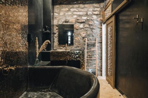 a bathroom with a large tub and a stone wall at The Yogi Surfer in Taghazout